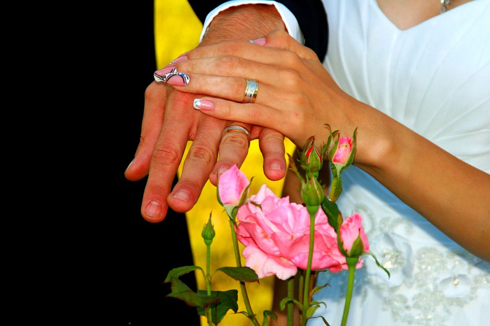 both hands of bride and groom with their wedding rings