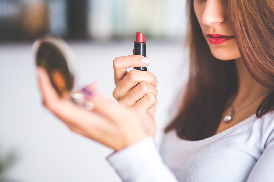 beautiful girl putting up a lipstick