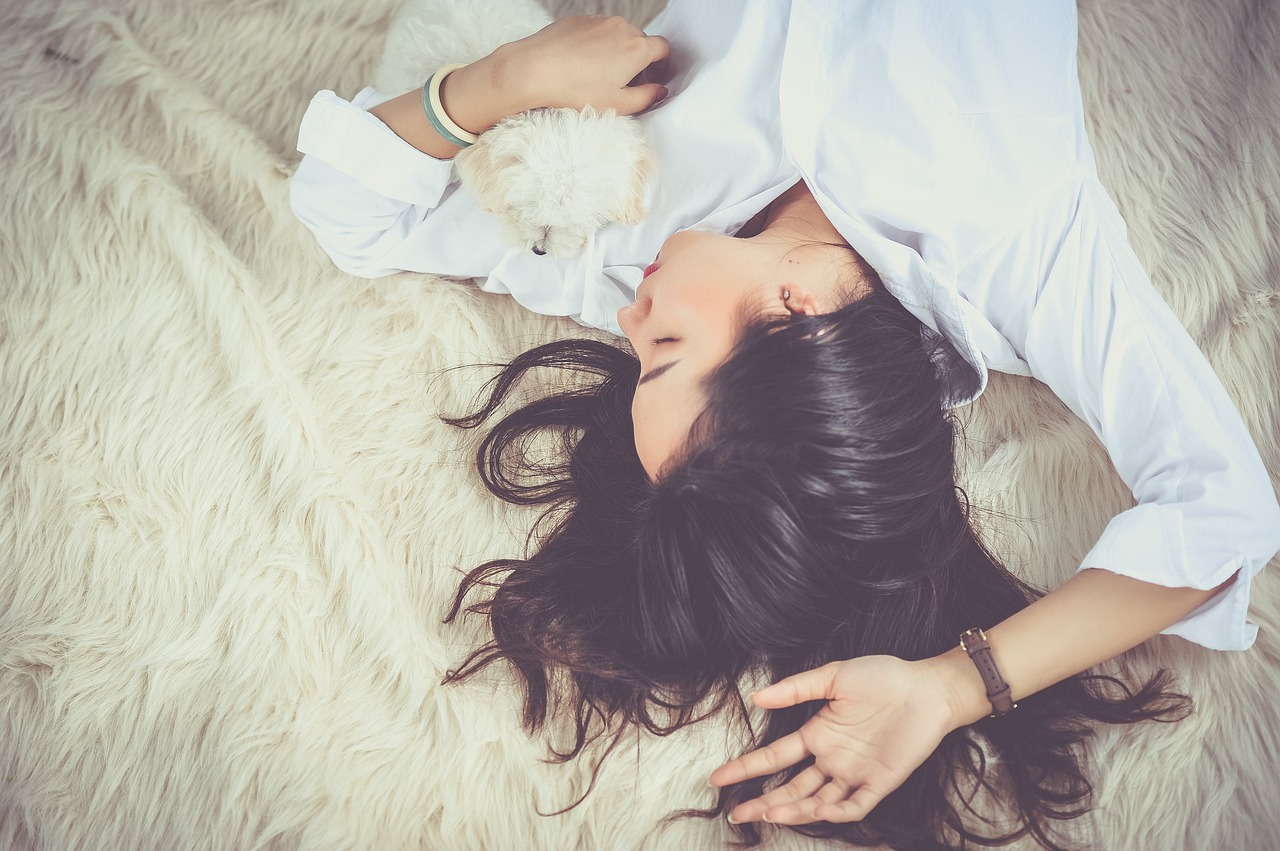 woman in white longsleeve sleeping with her dog