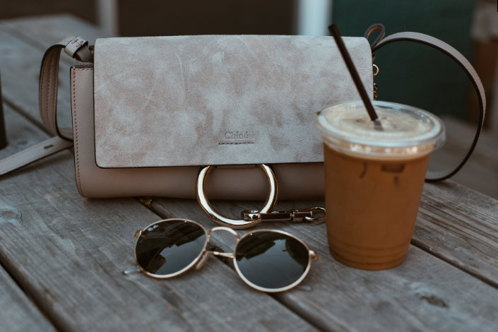 a bag and sunglasses on a wooden bench